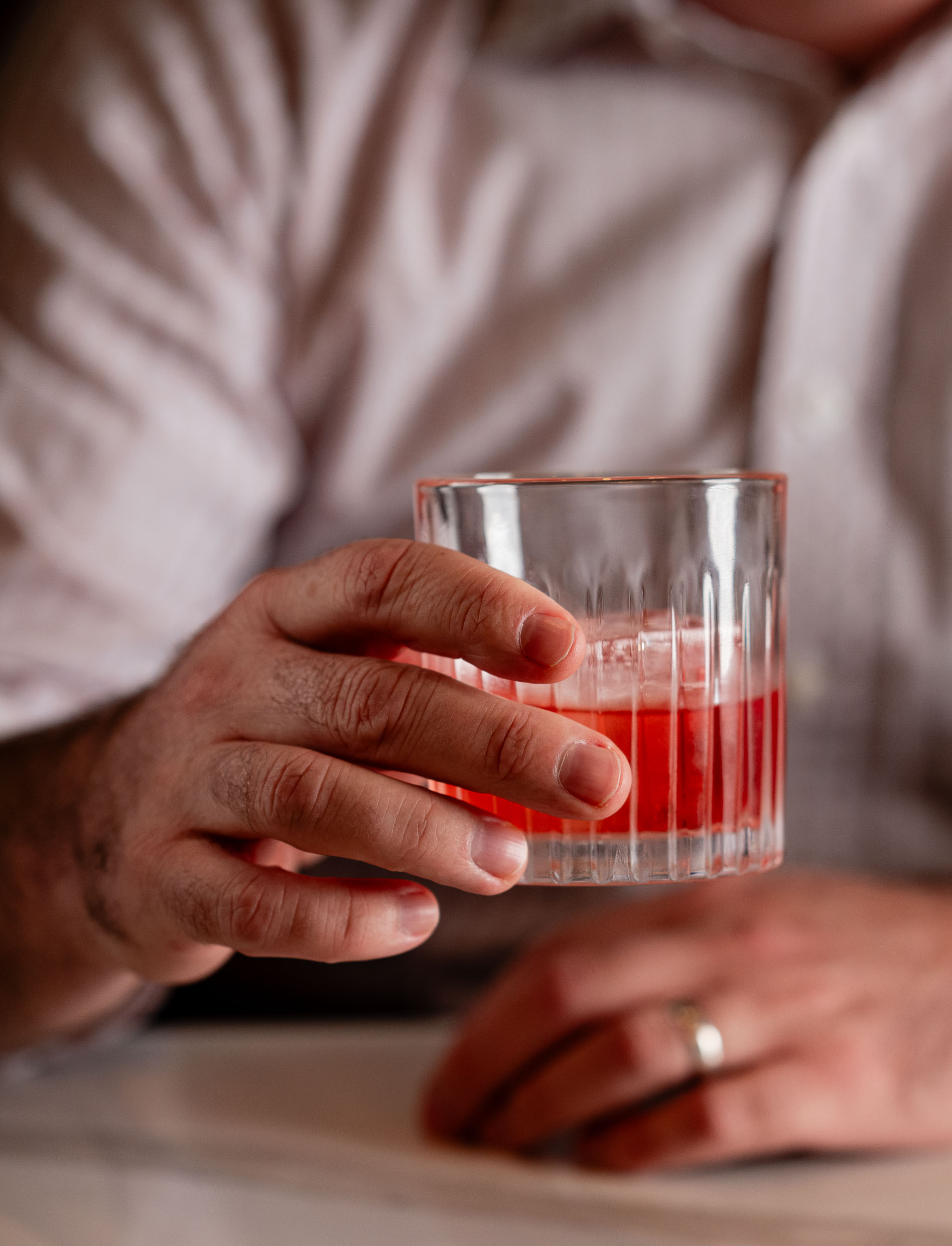 Gentleman's hand holding up a red craft cocktail